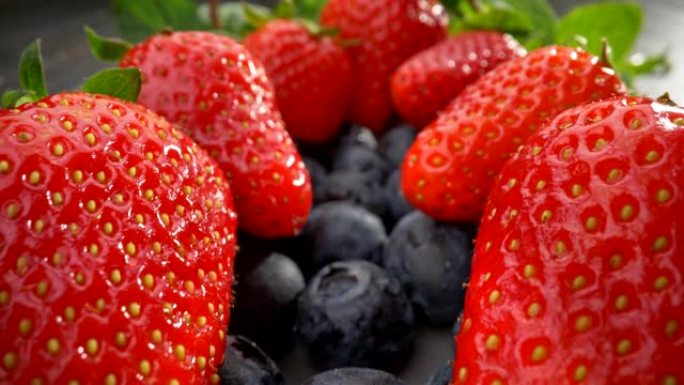 健康饮食。有益蓝莓之上的大红草莓。薄荷留在他们身后。UHD滑块镜头