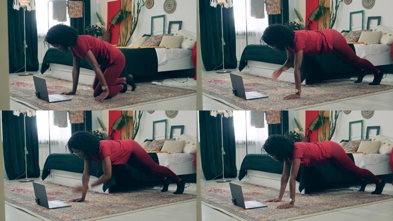 非洲女士正在用笔记本电脑在家锻炼。在家运动，在家健身的概念。