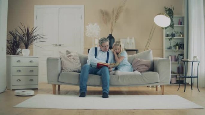爷爷和一个小女孩在沙发上看书