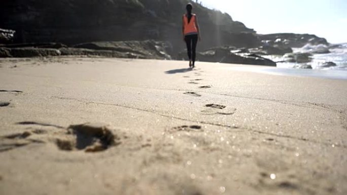 面目全非的女人赤脚走在海滩上，在沙滩上留下脚印