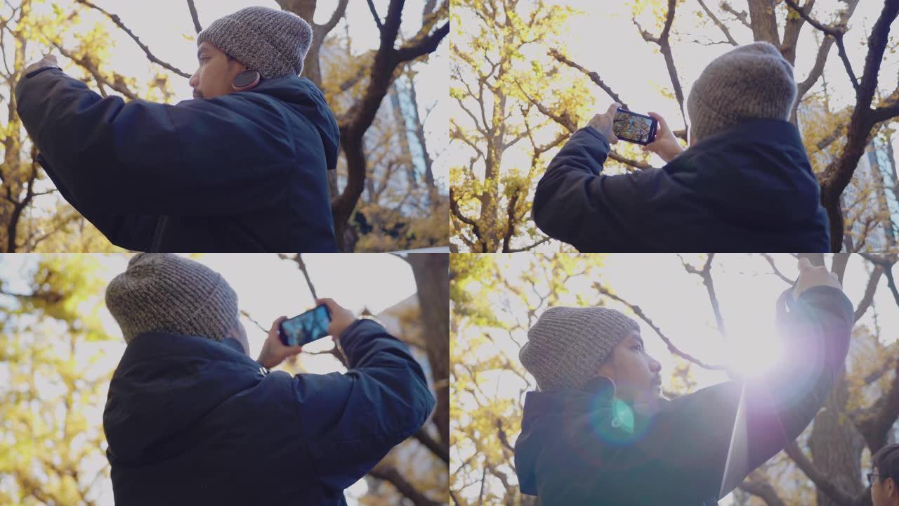 亚洲旅行者用智能手机拍摄秋叶照片。