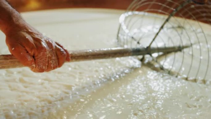 奶酪制造商的慢动作特写镜头正在按照古老的意大利传统使用新鲜和生物牛奶准备一种形式的帕尔马干酪
