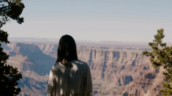 回顾年轻快乐的旅游女人在炎热阳光明媚的日子里看着令人难以置信的大峡谷史诗般的风景。