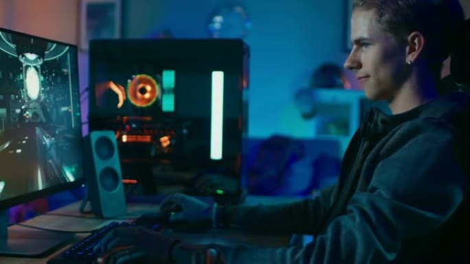 集中玩家在他强大的个人电脑上玩第一人称射击游戏在线视频游戏。房间和电脑有彩色霓虹灯。在家舒适的夜晚。
