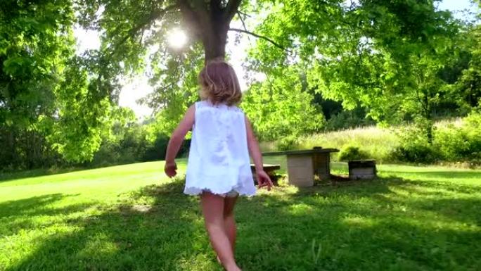 两岁的女孩奔向草地上的一棵树，并随着他的奔跑而成长。
