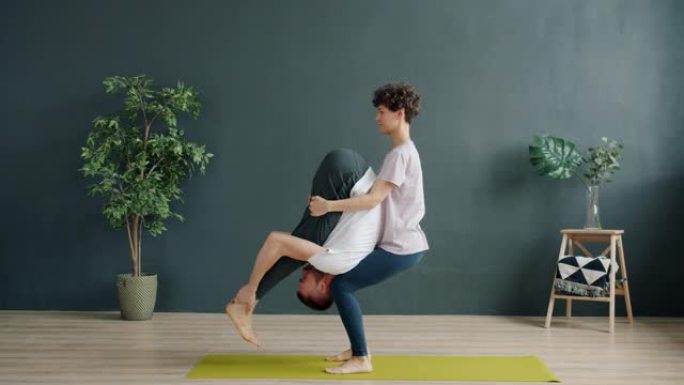 瑜伽老师和女学生在健身房做双人瑜伽，女孩举重男孩说话