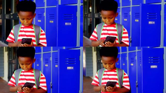 在学校走廊4k中使用手机的带书包的非洲裔美国小学生的前视图