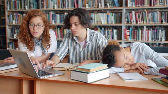 非裔美国女孩睡在桌子上时，学生在图书馆使用笔记本电脑