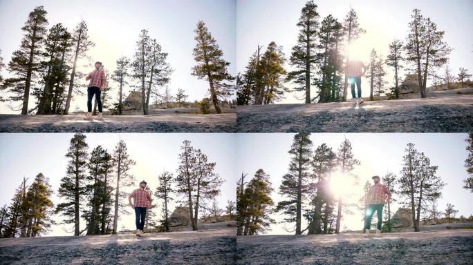 在优胜美地公园慢动作中，年轻人独自站在大石头上，太阳背光耀斑，令人惊叹的低角度拍摄。