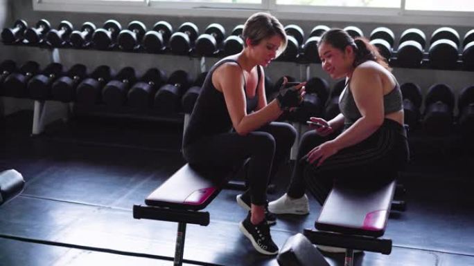 两个女人在健身房用手机观看
