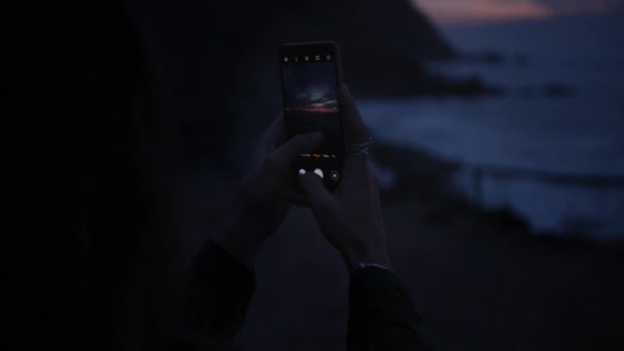 在海滩上用智能手机拍照的女人