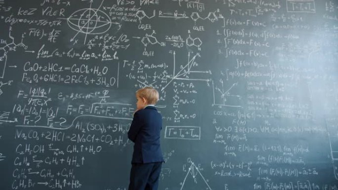 小男孩在大学里看着写在黑板墙上的公式