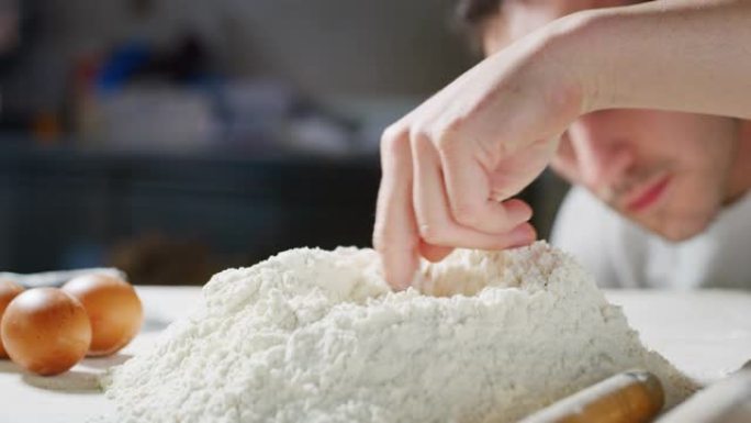 面包师在他的传统木桌上准备面粉，然后用手打一个洞，将鸡蛋扔在里面，制成真正的面团。