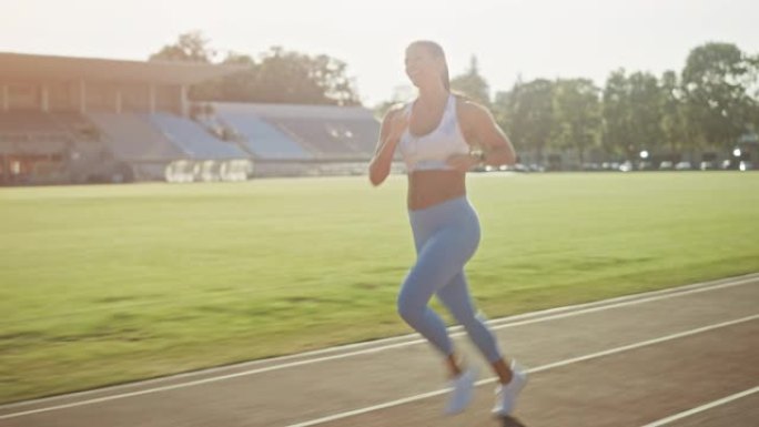 穿着浅蓝色运动上衣和打底裤的快乐微笑健身女子在体育场慢跑。在温暖的夏日，她跑得很快。运动员在做她的体
