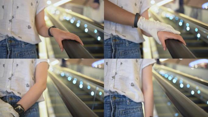 伸出塑料手套的手将女人的手从触摸自动扶梯扶手上移开