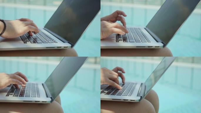 使用笔记本电脑坐在游泳池附近的女性特写镜头，慢动作