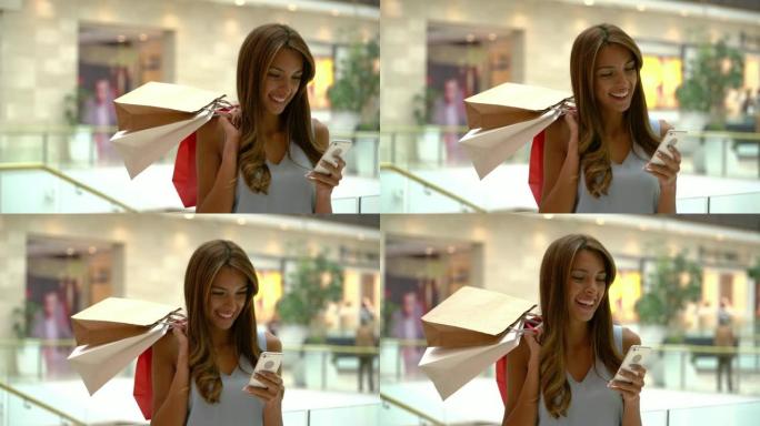 商场里美丽的年轻女子在智能手机上微笑着聊天