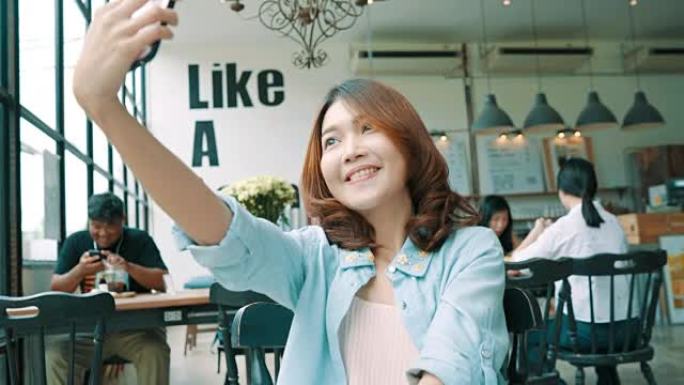 迷人的美丽快乐亚洲女性博客作者使用智能手机进行自拍，并为她的订阅者和她在咖啡馆和餐厅的频道录制食物v