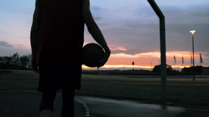 年轻男子女士在黄昏时走出室外篮球场