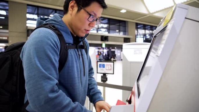 亚洲男子在机场用自助服务机办理登机手续