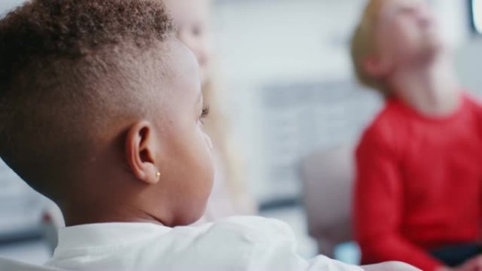 黑人男生坐在婴儿学校的椅子上与同学交谈的特写镜头