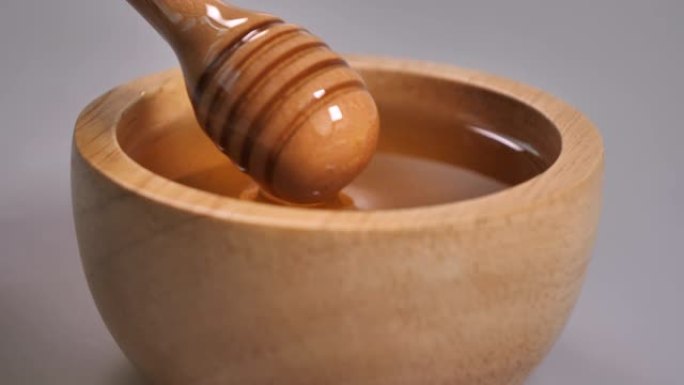 用金属勺子在木碗中取蜂蜜