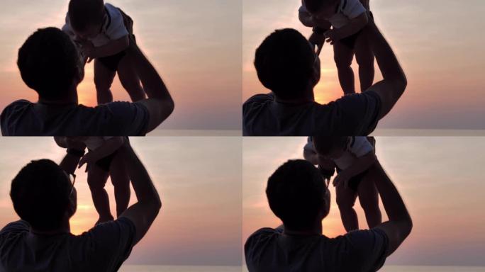 日落时在海滩上快乐的父亲和男婴的剪影。家庭关系，童年和父母观念。东南亚和东亚: 亚洲婴儿