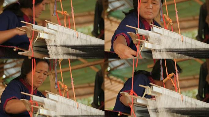 工艺村的传统纺织品制造，老妇女在木制织机上工作，纺纱制造丝绸或棉织物。泰国的丝织。