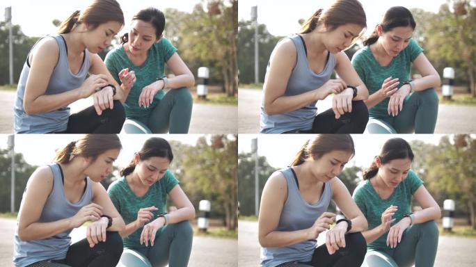 两名迷人的亚洲年轻女性看着一块智能手表一起锻炼