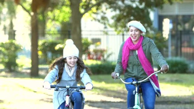 西班牙裔母亲和女儿在公园骑自行车