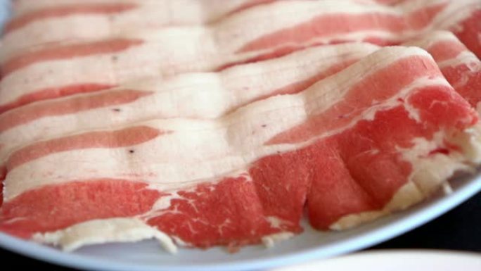 4k慢动作镜头特写，准备盘子里的猪肉培根肉切片，sha锅和Sukiyaki日式食品概念