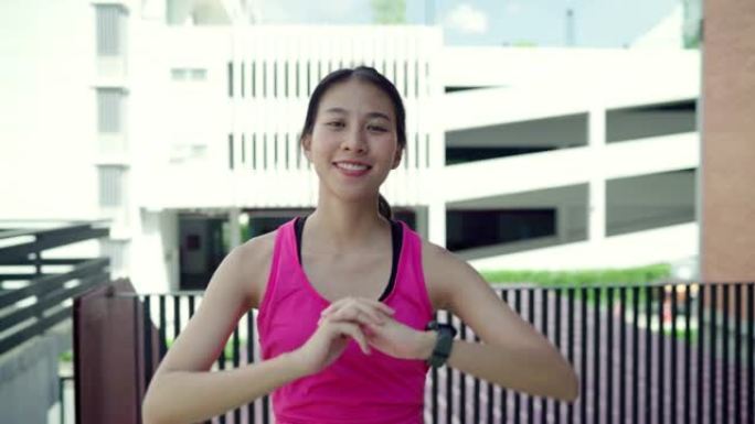 慢动作-健康美丽的年轻亚洲跑步者女人在城市的街道上跑步后，微笑着看着镜头。生活方式适合和积极的女性在