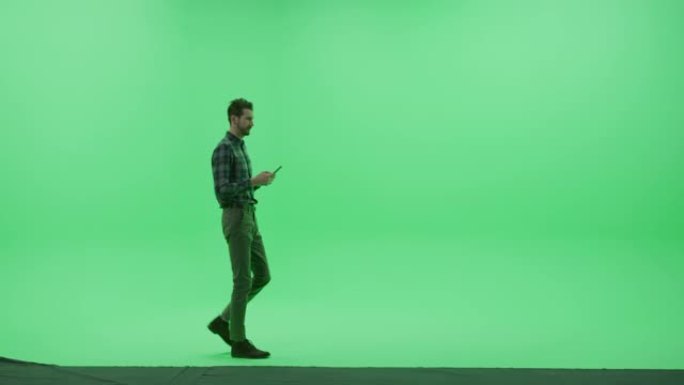 绿屏Chroma Key Studio: 强壮的男人穿着便服，使用智能手机设备，写电子邮件，进行远程