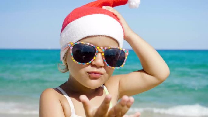 一个小女孩穿着圣诞老人的帽子，穿着泳衣，戴着墨镜，海蓝色的海水背景，在海上玩耍。