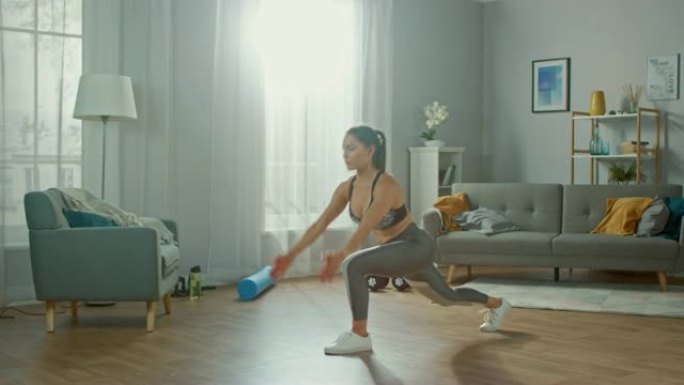 穿着运动上衣的美丽自信丰满的健身女孩正在她明亮宽敞的公寓里做伸展瑜伽练习，室内简约。