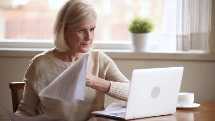 持有账单的老年压力重重的妇女使用笔记本电脑支票在线付款