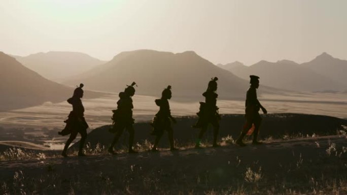 纳米比亚纳米布沙漠中，穿着传统服装的希姆巴部落的人们沿着一条以风景优美的山脉为背景的小路行走的4K画