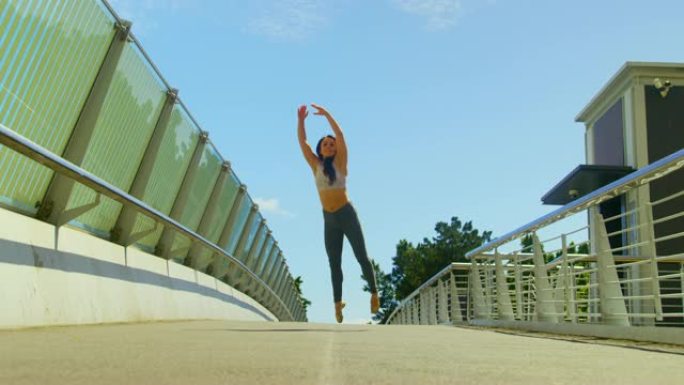 年轻的女舞者在城市4k的一座桥上跳舞