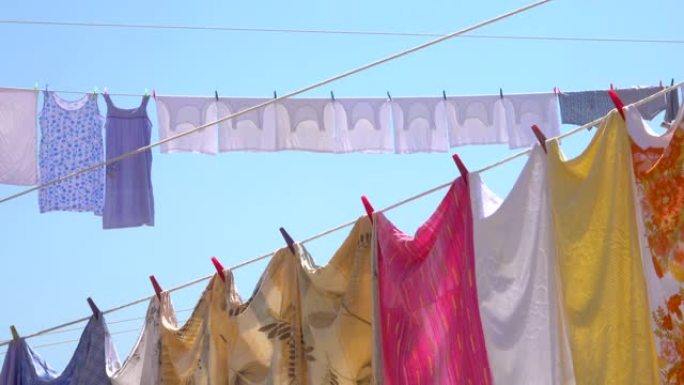 特写: 五颜六色的床单、衣服、毛巾挂在夏天的空气中晾干。