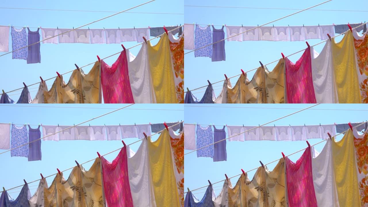 特写: 五颜六色的床单、衣服、毛巾挂在夏天的空气中晾干。