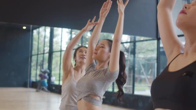 年轻的亚洲运动人士与教练一起练习瑜伽课。亚洲妇女团体在健身工作室锻炼健康的生活方式。体育活动、体操或