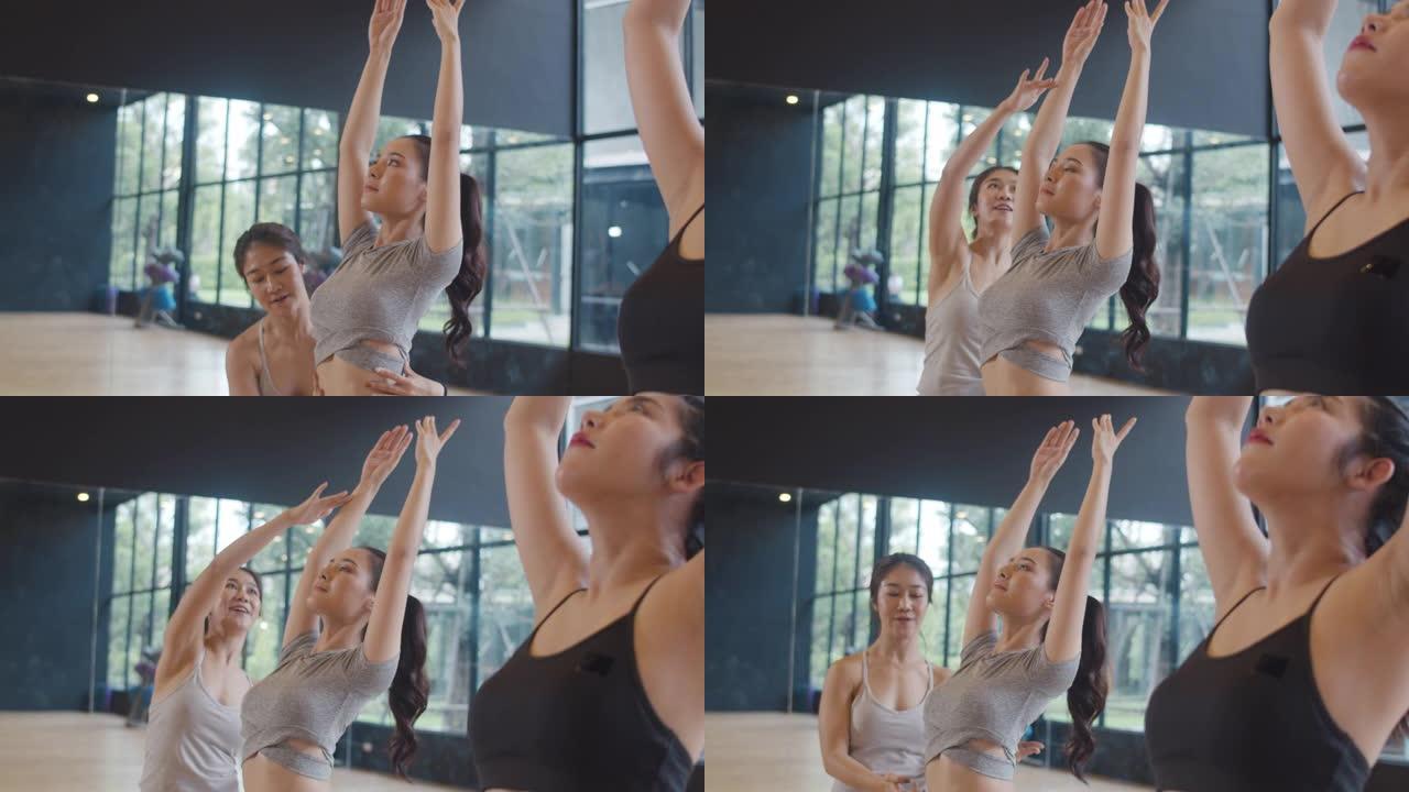 年轻的亚洲运动人士与教练一起练习瑜伽课。亚洲妇女团体在健身工作室锻炼健康的生活方式。体育活动、体操或