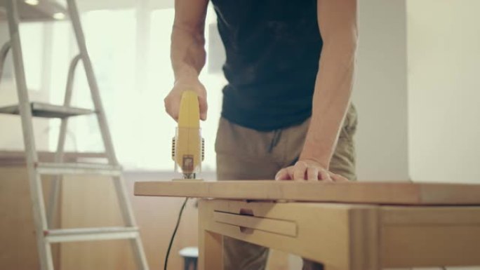 家庭自制。男人剪掉木制家具。