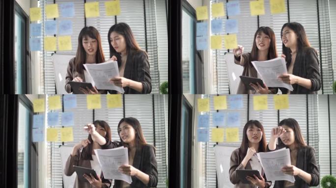 女性头脑风暴使用粘性笔记在创意办公室