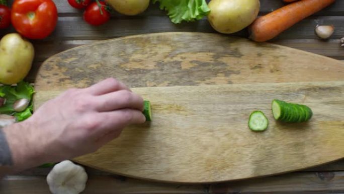 厨师在木板上切黄瓜的手的特写