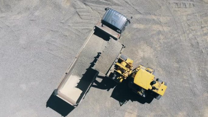 拖拉机正在将砾石放入卡车后部的俯视图