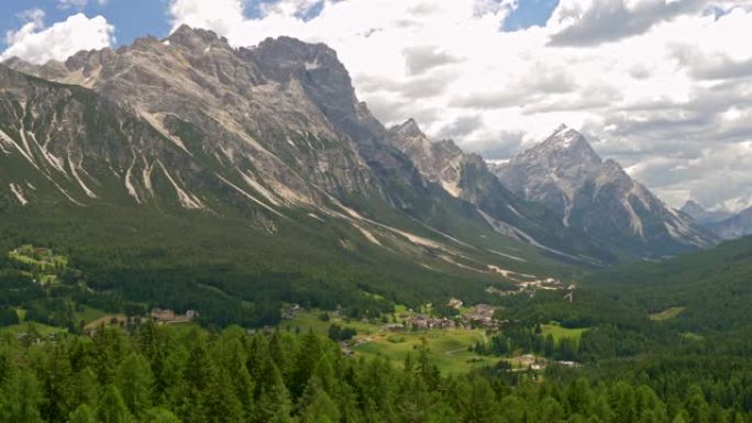意大利科尔蒂纳丹佩佐镇的山谷。多洛米蒂山脉 (意大利阿尔卑斯山) 和山谷中的松树林的全景，在多云的天