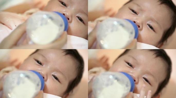 母亲用瓶子里的牛奶喂养亚洲新生女孩