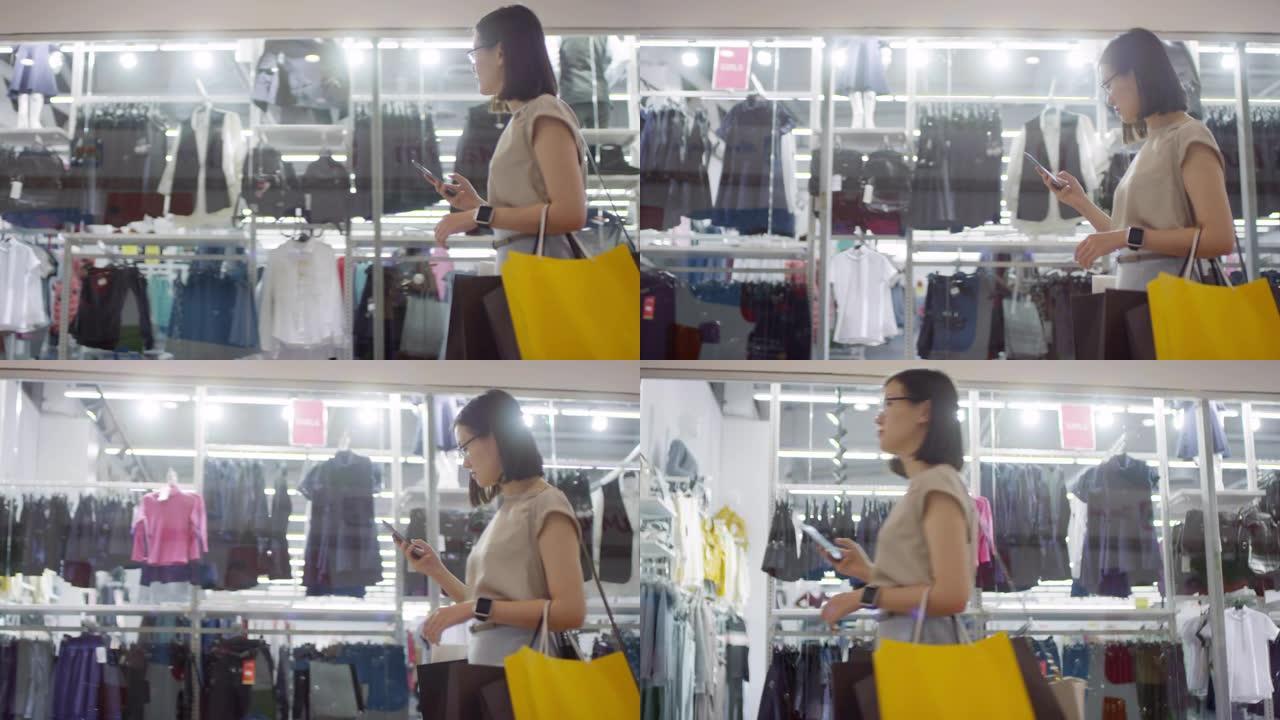 亚洲妇女带着购物袋走过商场的零售店