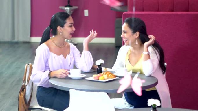 两名西班牙裔妇女在咖啡，糕点上聊天